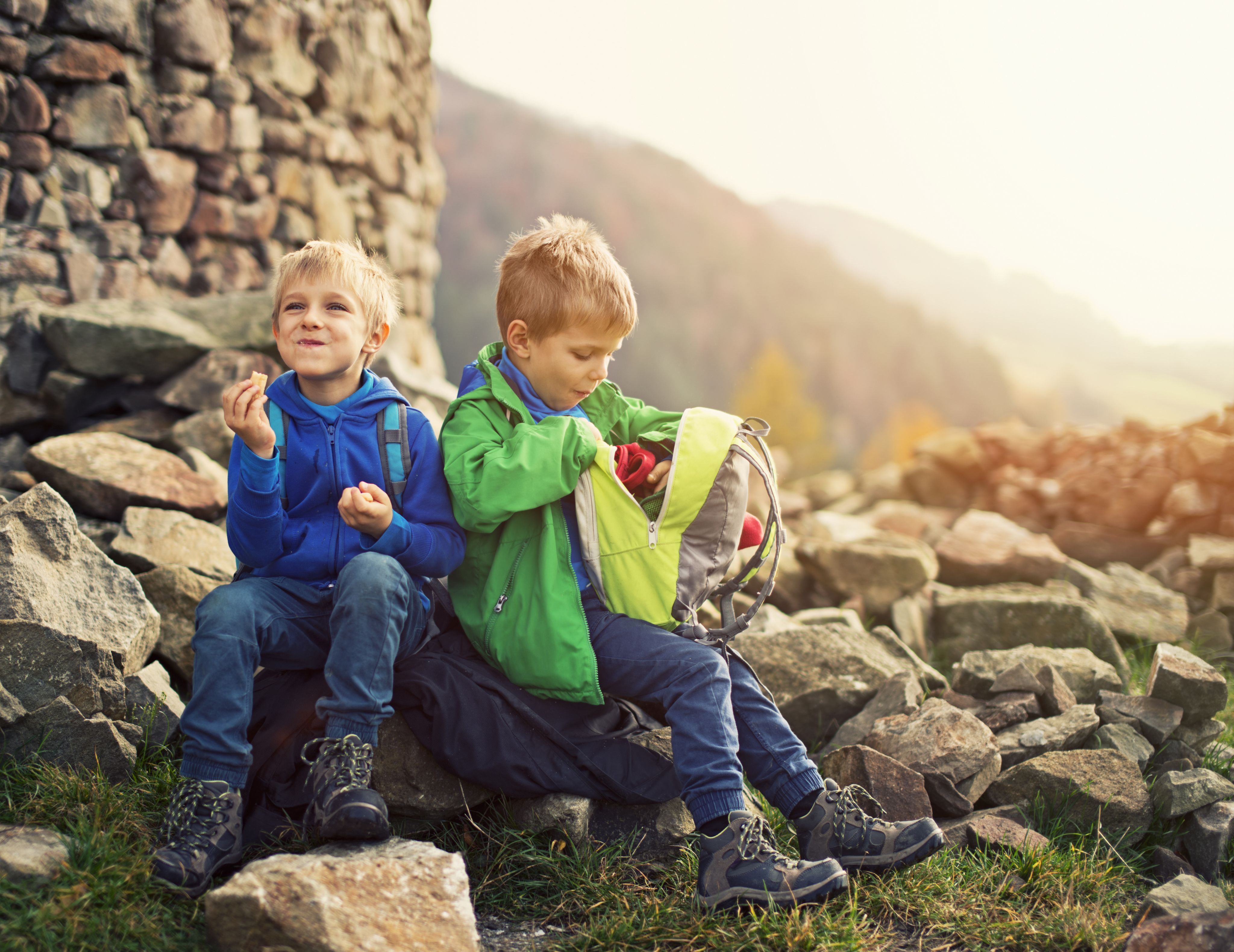 Two young boys eating on a rocky outcrop