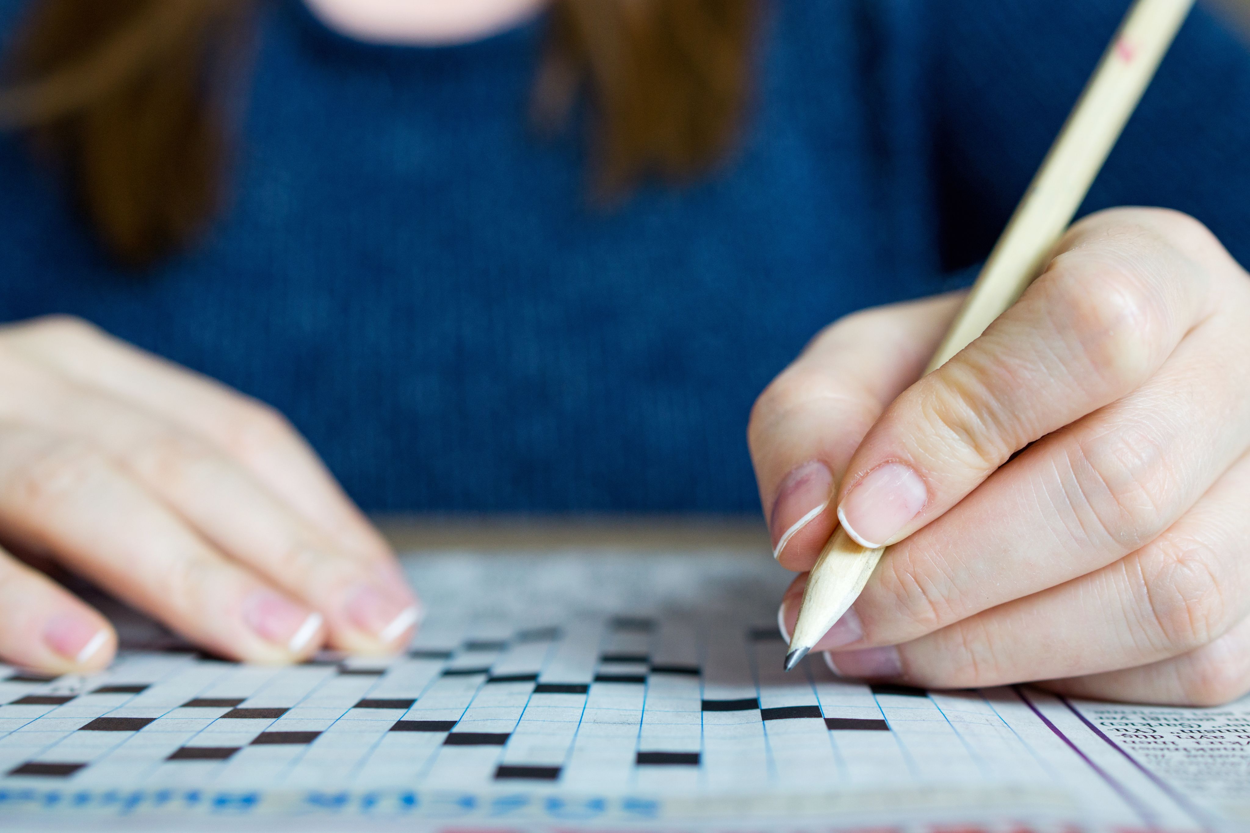 Close-up of person completing a crossword on paper
