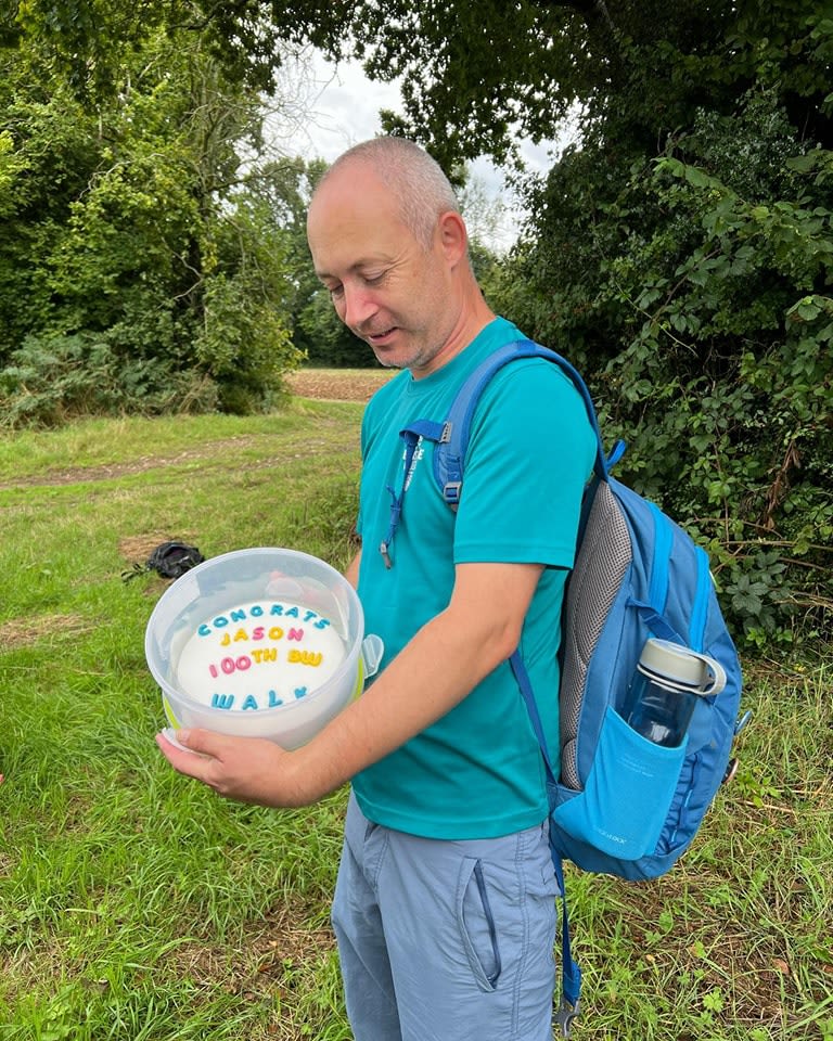 Jason Collins-Owen holding a cake to celebrate his 100th walk